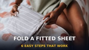 Woman folding a fitted sheet neatly on a bed — how to fold a fitted sheet in 6 steps
