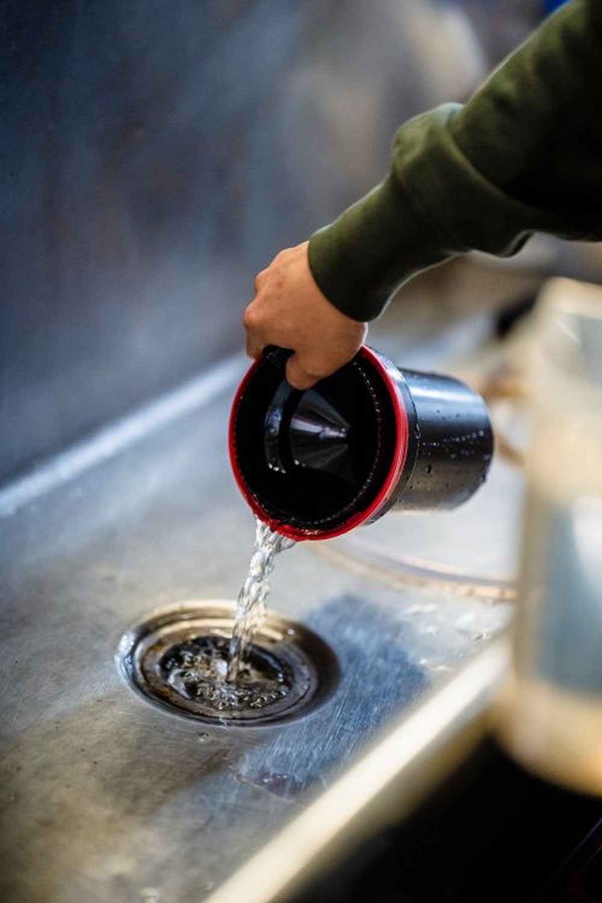 Pouring baking soda and vinegar into a sink drain to unclog it without a plumber