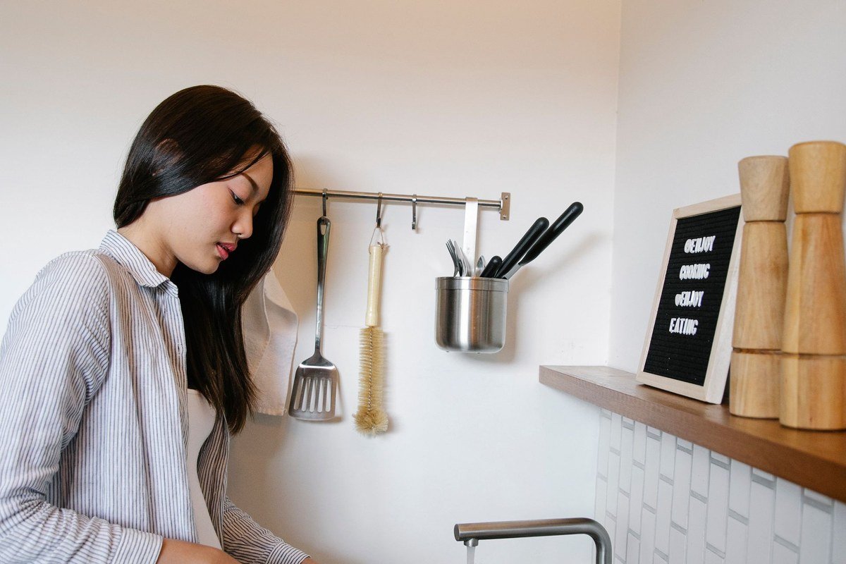 wiping a pan clean at a kitchen sink after soaking