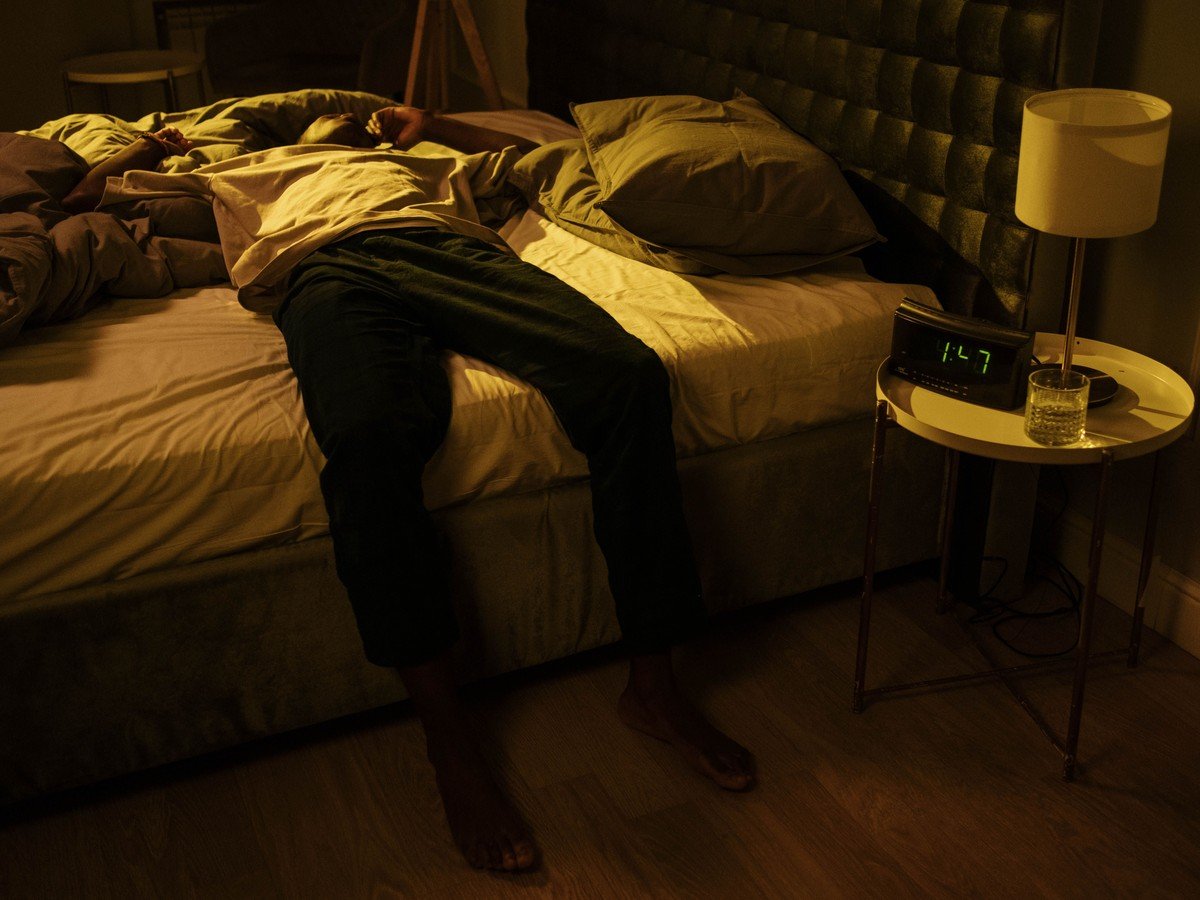 A man lying awake in bed at night while his partner snores — a common reason people search how to stop snoring in 5 minutes