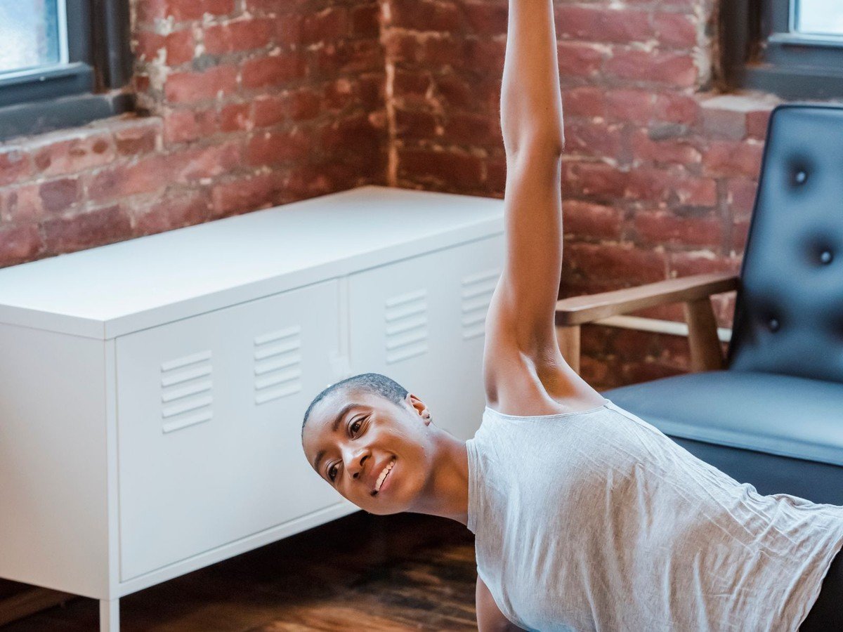 Woman doing a side plank on a yoga mat in her apartment