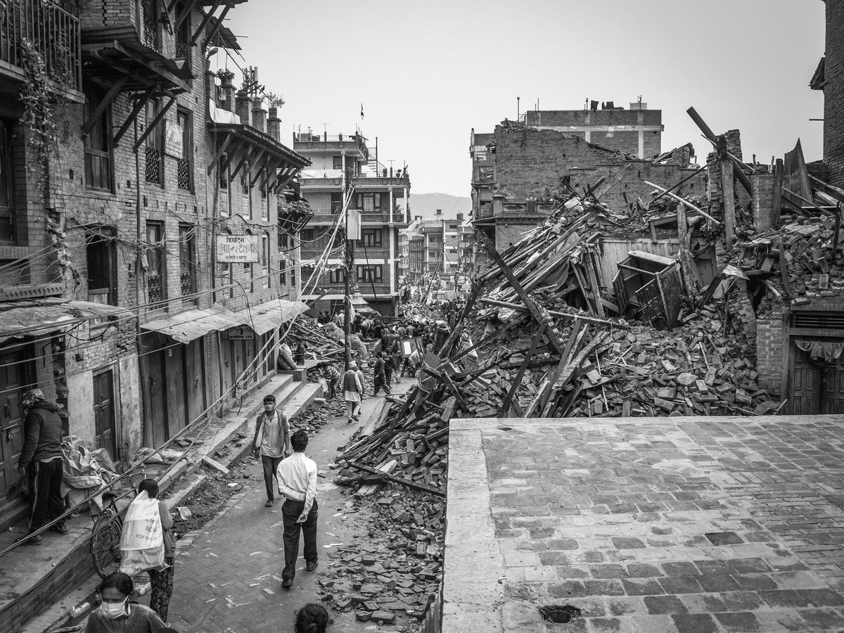 Damaged street with cracked buildings and debris after an earthquake (illustrative photo)