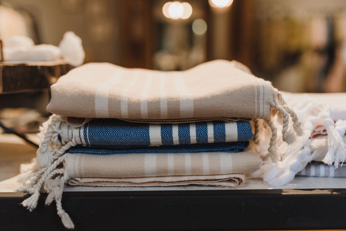 Neatly folded fitted sheets stacked in a linen closet.