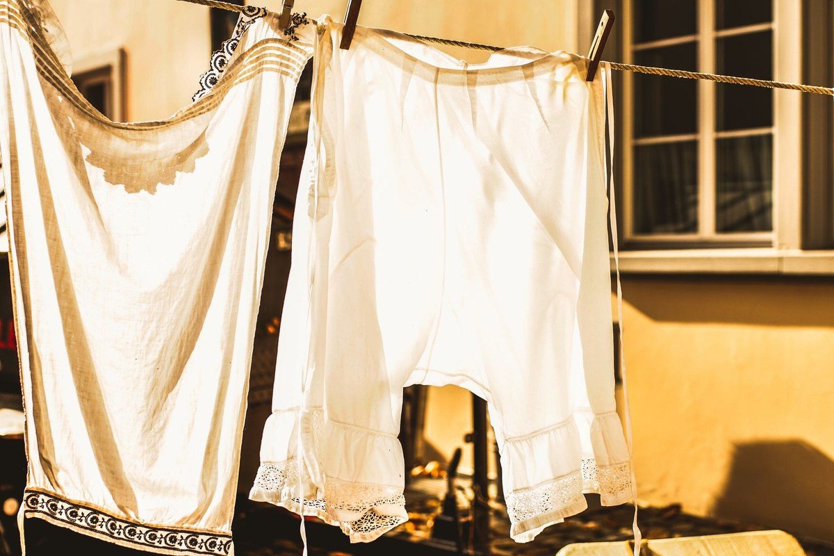 White clothes drying on a sunlit clothesline — sunlight kills odor-causing bacteria