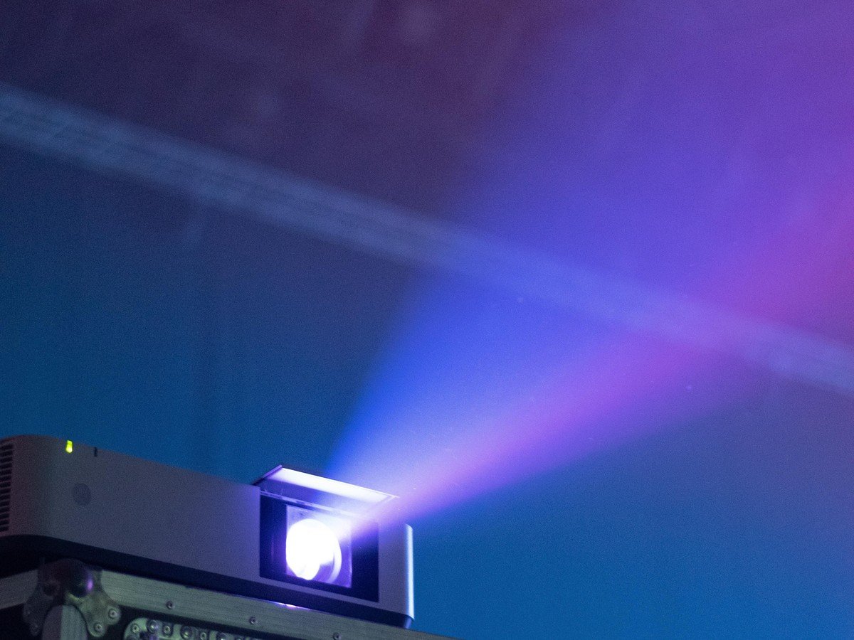 film projector beaming in a dark cinema — Warner Bros faces a reported $250 million loss on the Tom Cruise Digger flop