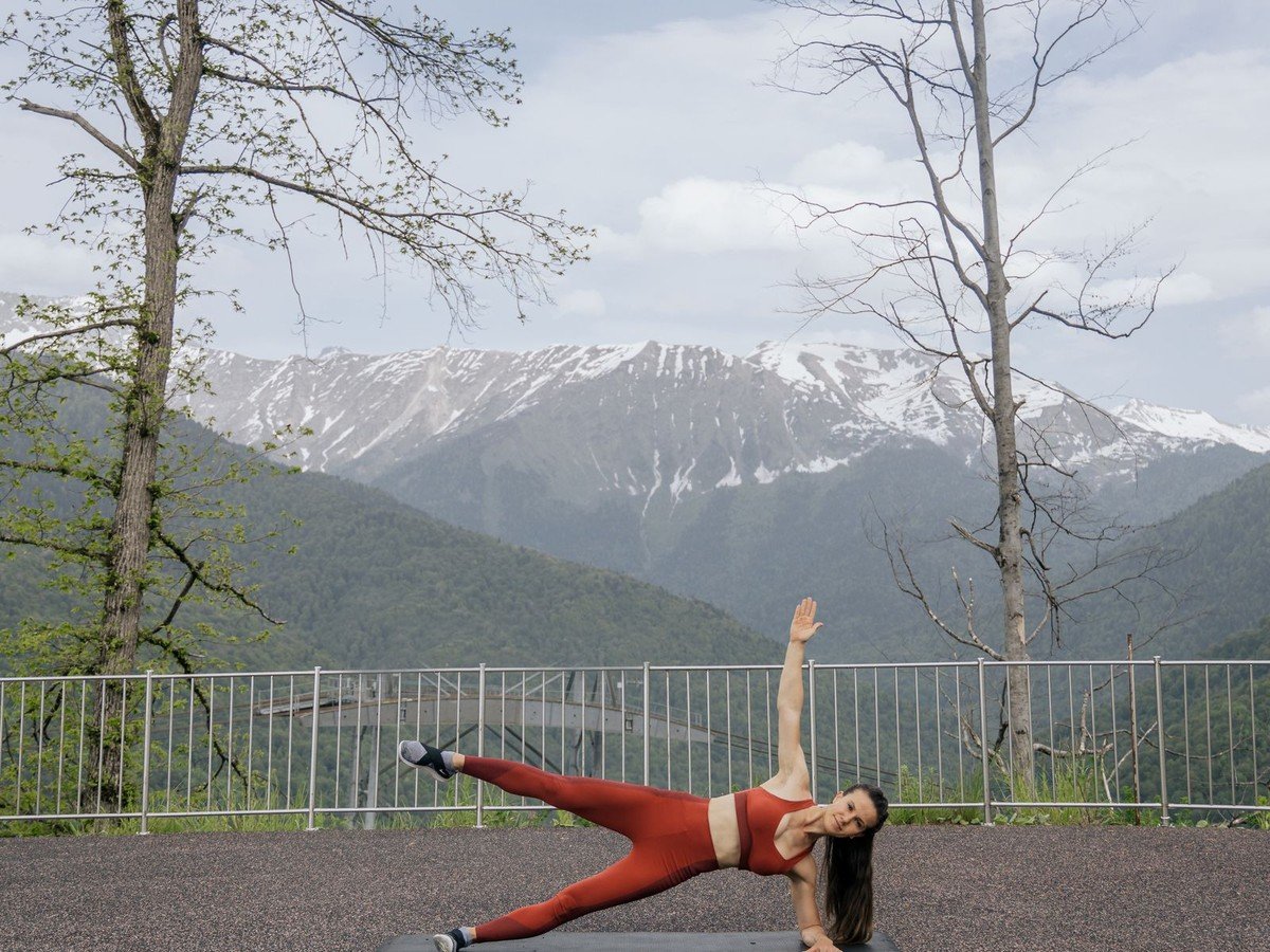Woman doing a side plank exercise outdoors on a yoga mat