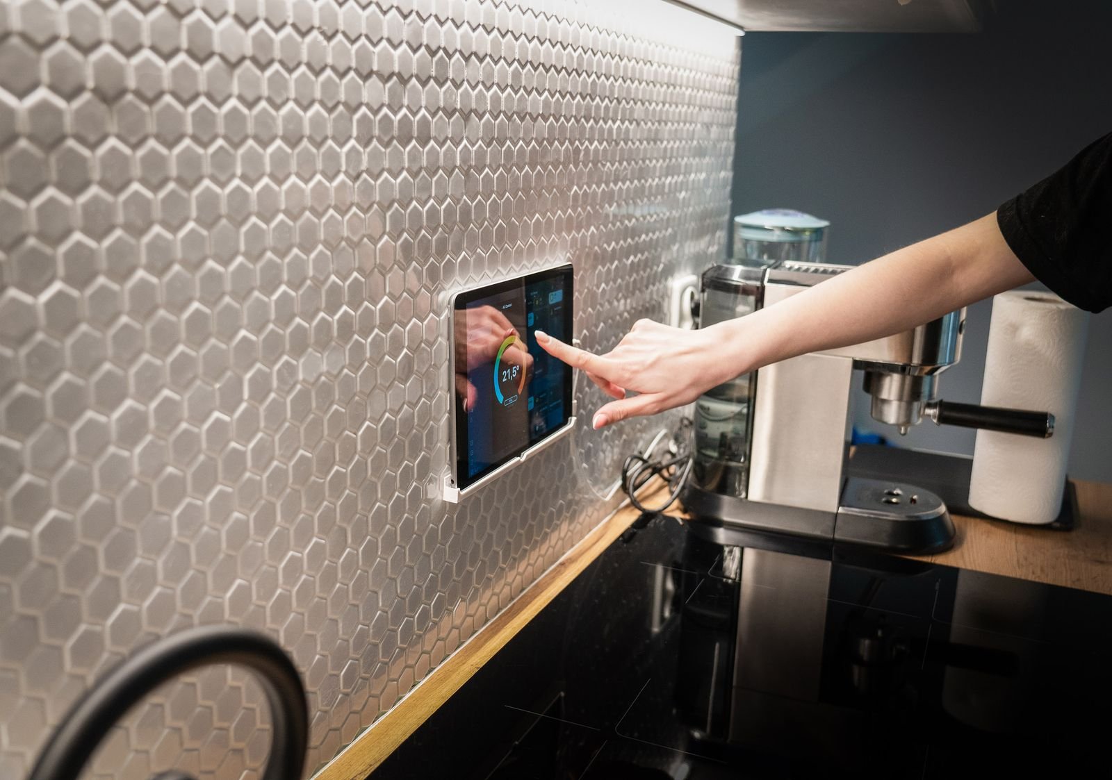 Hand adjusting a wall-mounted smart home control panel in a kitchen, like the rumored wall-mounted Apple HomeView