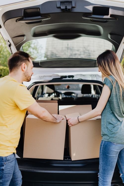 Cardboard moving boxes being loaded into a car trunk during a move