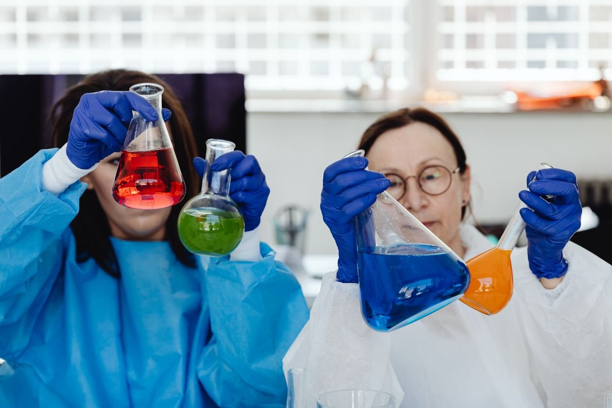 Scientists holding colorful chemistry glassware, illustrating the mirror-image molecule research behind the Nobel Prize Chemistry 2026 winners